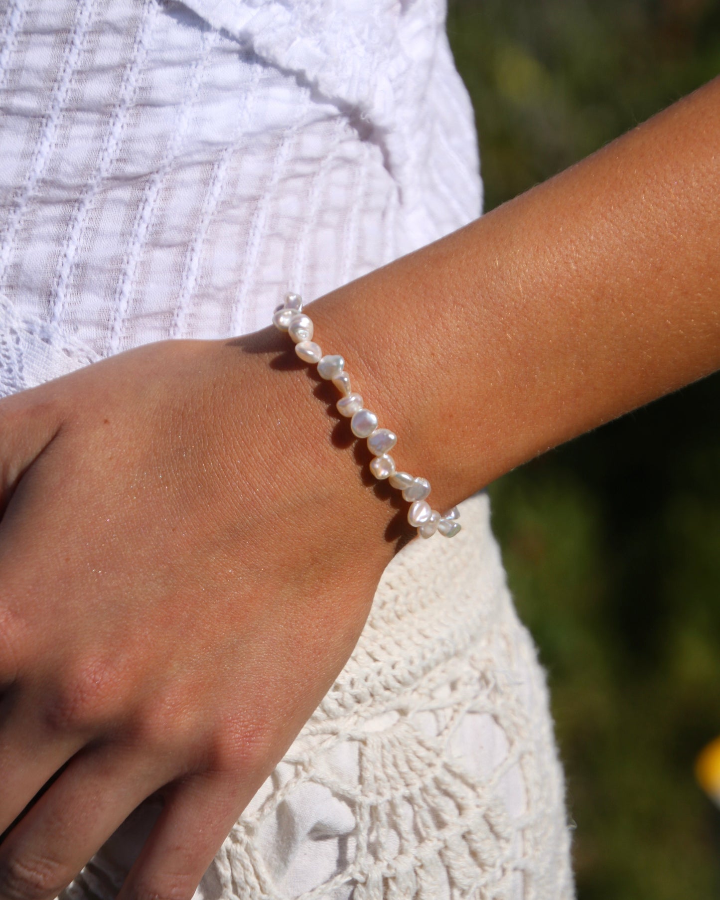 Pearl bracelet on a wrist with a blurred natural background