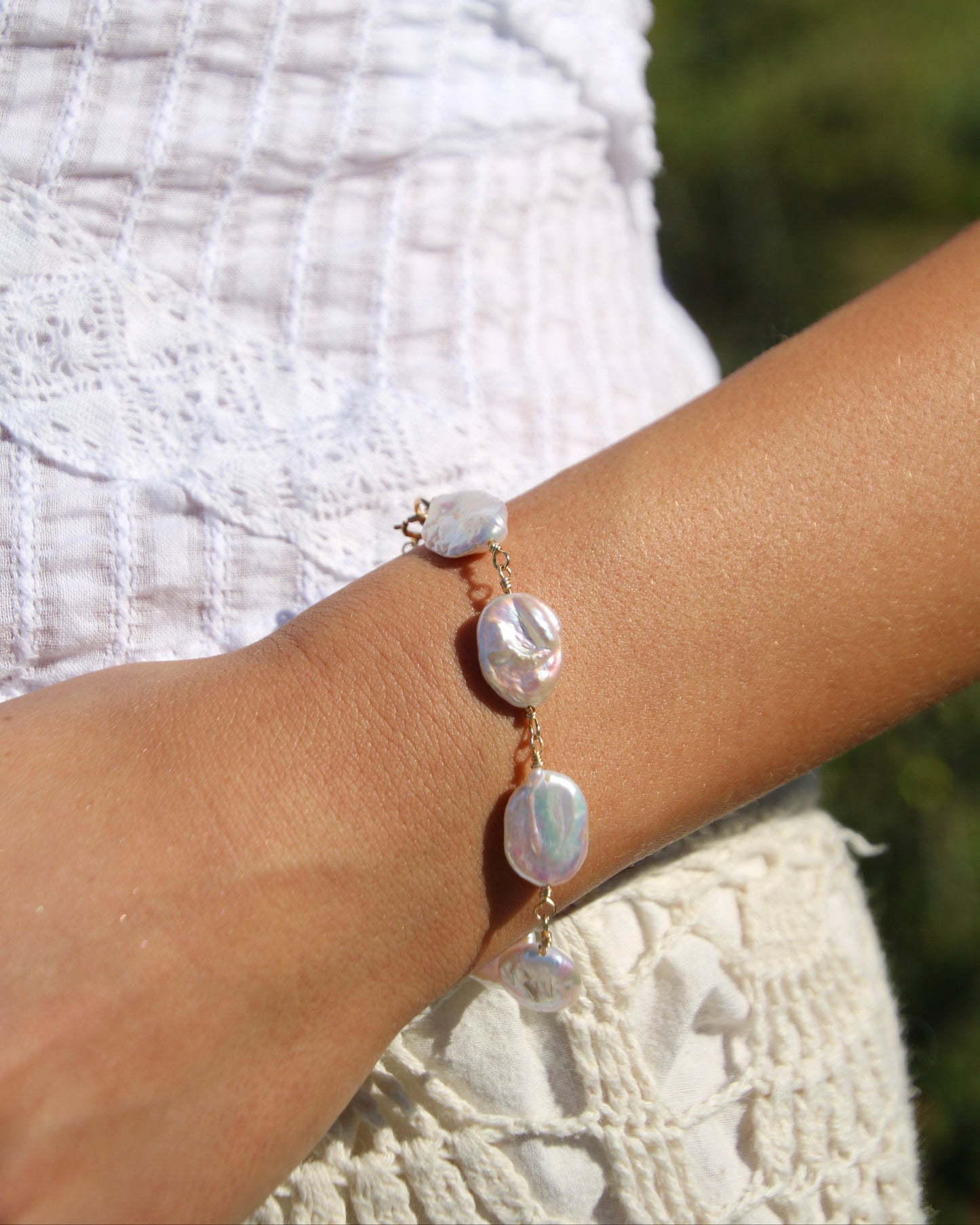 Pearl bracelet on a wrist with a blurred natural background