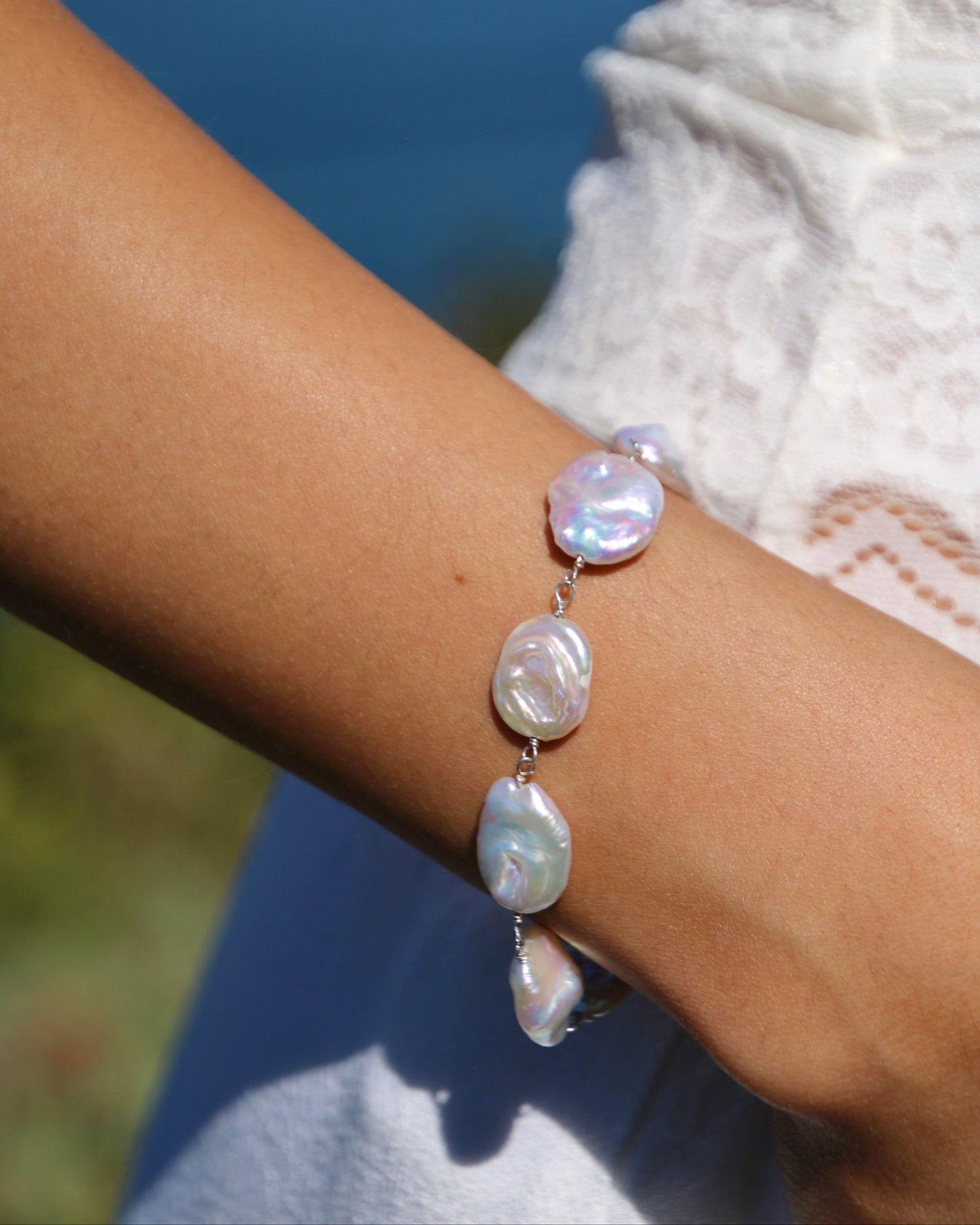 Pearl bracelet on a wrist with a blurred natural background